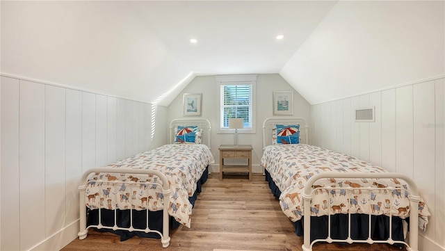 bedroom featuring wood walls, lofted ceiling, and hardwood / wood-style flooring