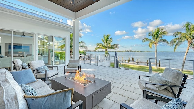 view of patio with a water view and an outdoor living space with a fire pit