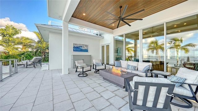 view of patio with ceiling fan and an outdoor living space with a fire pit