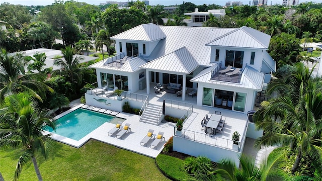 rear view of house with outdoor lounge area, a yard, pool water feature, a balcony, and a patio