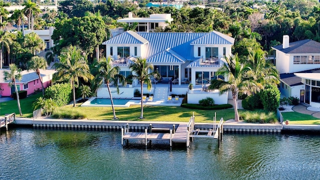 back of property with a balcony, a patio, and a water view