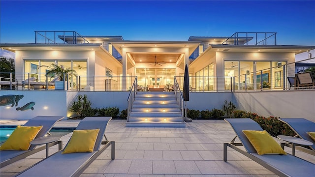 patio terrace at dusk featuring ceiling fan and a pool