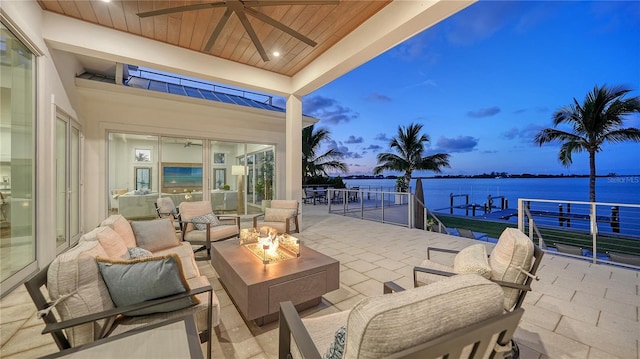 patio terrace at dusk featuring a water view and an outdoor living space with a fire pit