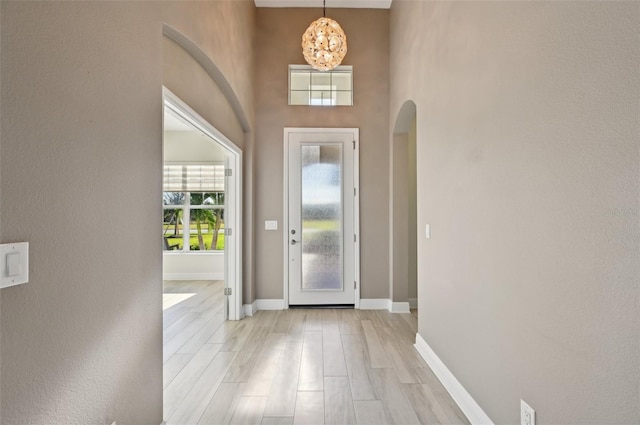 entrance foyer featuring a notable chandelier, a high ceiling, and light wood-type flooring