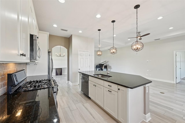 kitchen featuring white cabinetry, an island with sink, stainless steel appliances, and decorative light fixtures