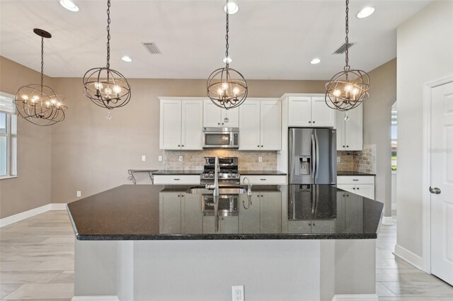 kitchen with white cabinetry, hanging light fixtures, appliances with stainless steel finishes, and dark stone counters