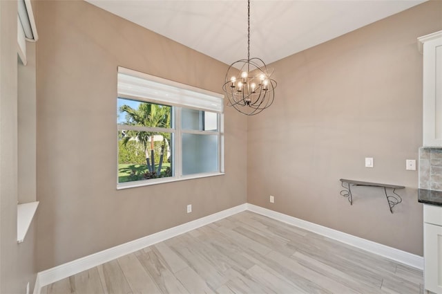 unfurnished dining area featuring an inviting chandelier and light hardwood / wood-style flooring