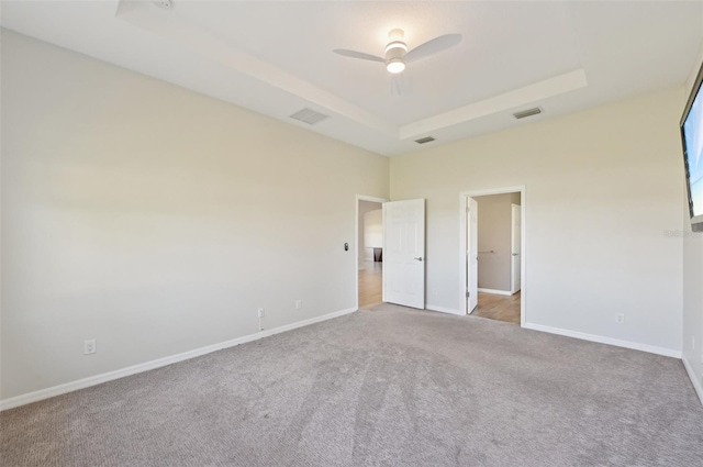 unfurnished bedroom with a raised ceiling, ceiling fan, and light colored carpet