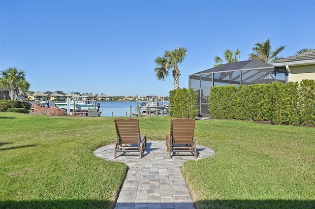 view of yard with glass enclosure, a dock, and a water view