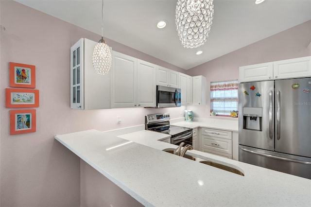 kitchen with pendant lighting, white cabinets, sink, vaulted ceiling, and appliances with stainless steel finishes