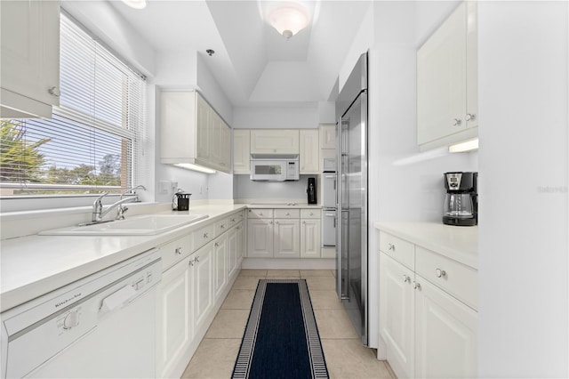 kitchen featuring white cabinets, white appliances, sink, and light tile patterned floors