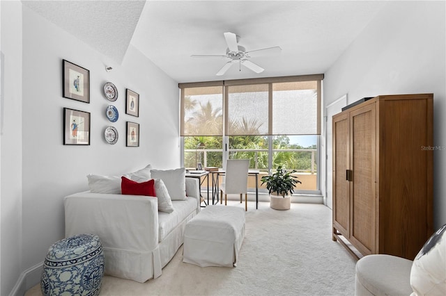 living area featuring a textured ceiling, ceiling fan, floor to ceiling windows, and light carpet