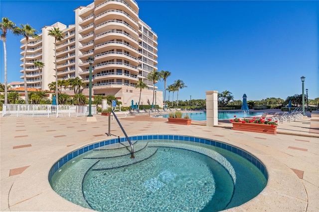 view of pool with a hot tub and a patio area