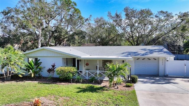 single story home with a porch, a front yard, and a garage