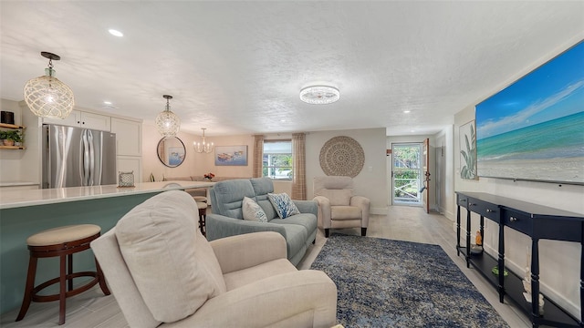 living room featuring a textured ceiling, light wood-type flooring, and a notable chandelier