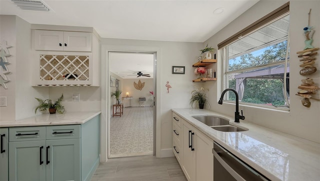 kitchen with stainless steel dishwasher, ceiling fan, light stone counters, and sink