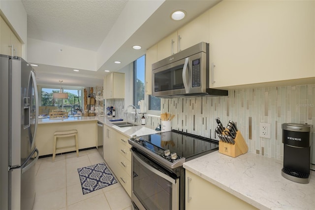 kitchen with light tile patterned floors, sink, appliances with stainless steel finishes, and cream cabinets