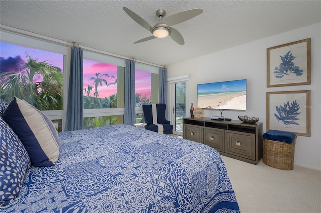 bedroom with ceiling fan, light colored carpet, and a textured ceiling