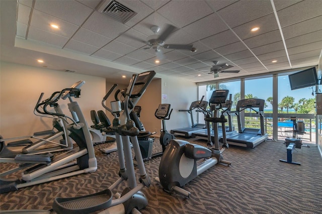 workout area with carpet, a paneled ceiling, expansive windows, and ceiling fan