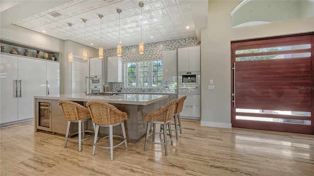 kitchen with pendant lighting, a center island, white cabinetry, a breakfast bar area, and beverage cooler