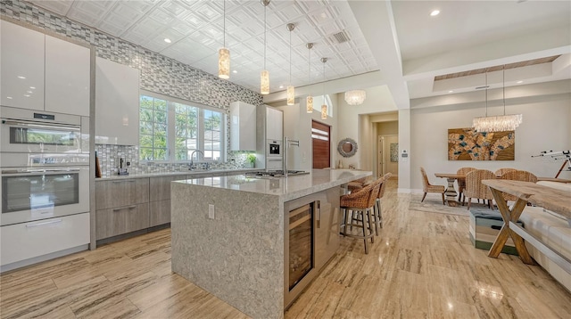 kitchen with light stone countertops, stainless steel appliances, a kitchen island, decorative light fixtures, and white cabinets