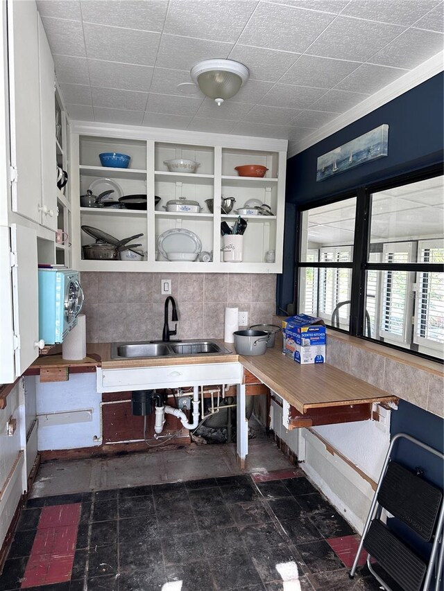 kitchen featuring backsplash, ornamental molding, sink, built in features, and white cabinets