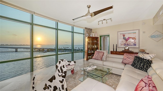 living room featuring ceiling fan, expansive windows, and a water view