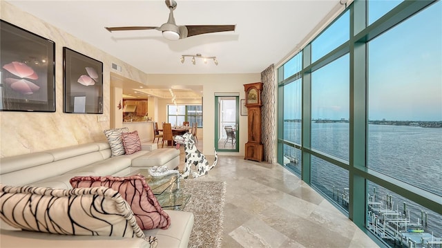 living room with floor to ceiling windows, a water view, and ceiling fan