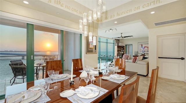 dining room featuring ceiling fan and a water view