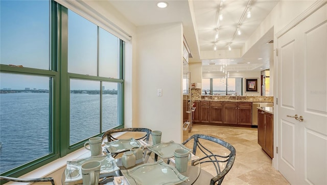 tiled dining area featuring a healthy amount of sunlight, a water view, and rail lighting