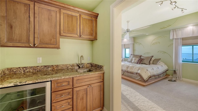 interior space featuring carpet flooring, light stone counters, ceiling fan, sink, and wine cooler