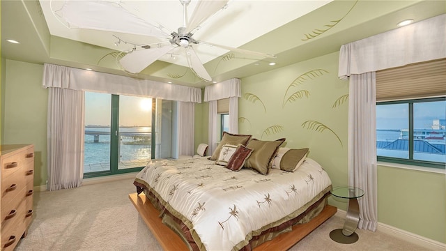 bedroom with a water view, ceiling fan, and light colored carpet