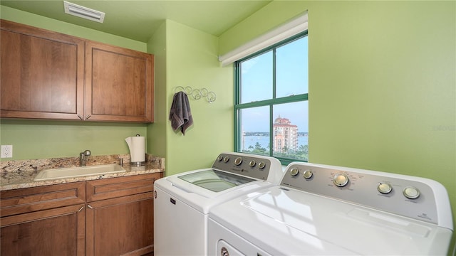 washroom featuring washing machine and dryer, sink, and cabinets