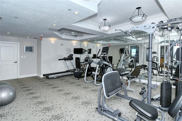 gym with a textured ceiling, a raised ceiling, ceiling fan, and ornamental molding