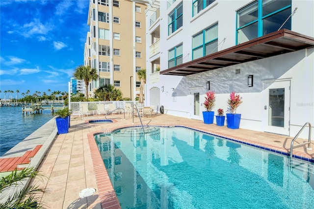 view of swimming pool featuring a patio and a water view