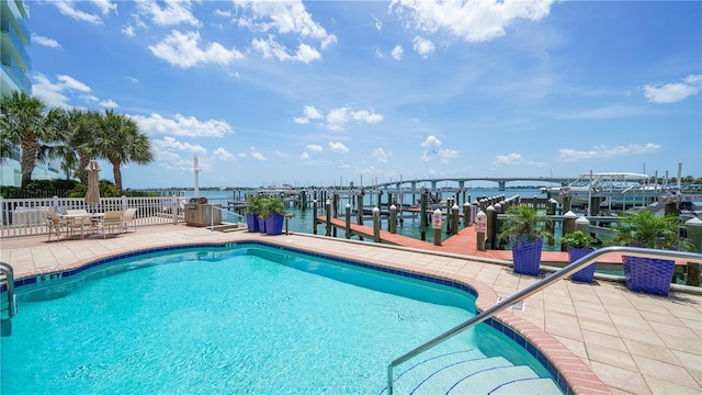 view of swimming pool featuring a boat dock, a water view, and a patio