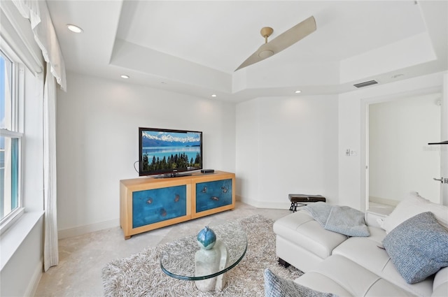 living room with recessed lighting, a tray ceiling, and baseboards