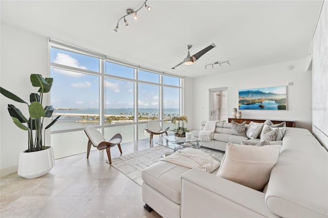 tiled living room with track lighting, a wall of windows, a water view, and ceiling fan