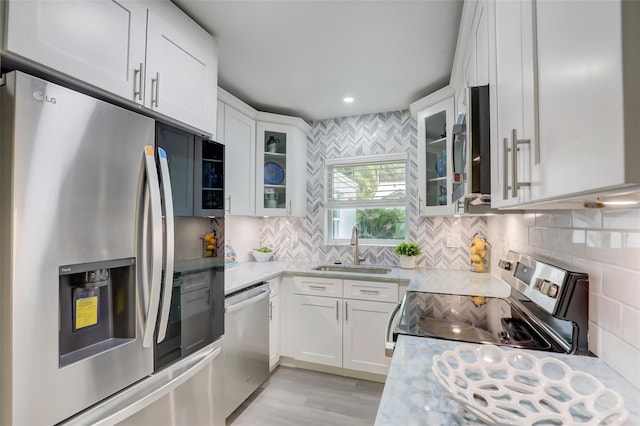 730 40th St, Sarasota, FL 34234 - kitchen featuring stainless steel appliances, white cabinets, tasteful backsplash, glass insert cabinets, and light wood finished floors
