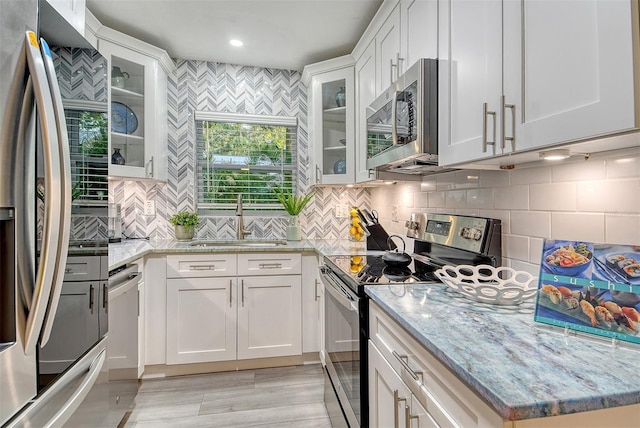 730 40th St, Sarasota, FL 34234 - kitchen with stainless steel appliances, white cabinetry, backsplash, light stone counters, and recessed lighting