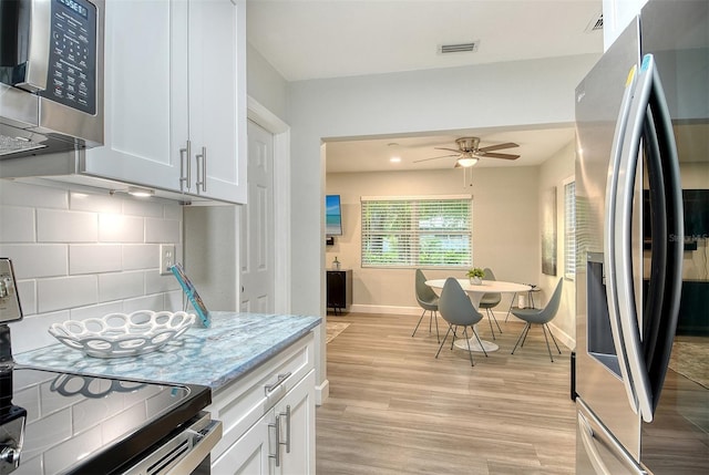 730 40th St, Sarasota, FL 34234 - kitchen featuring appliances with stainless steel finishes, light wood-style flooring, decorative backsplash, a ceiling fan, and white cabinets