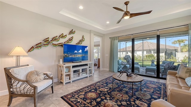 living room with light tile patterned floors, a tray ceiling, and ceiling fan