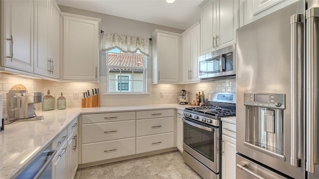 kitchen featuring decorative backsplash, light stone counters, white cabinetry, and appliances with stainless steel finishes