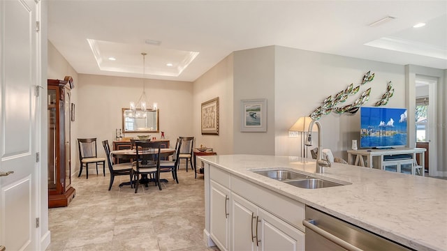 kitchen featuring white cabinets, pendant lighting, a raised ceiling, and sink