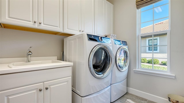 washroom featuring light tile patterned flooring, cabinets, sink, and washing machine and clothes dryer