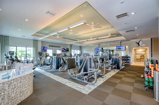 exercise room with a tray ceiling and ceiling fan