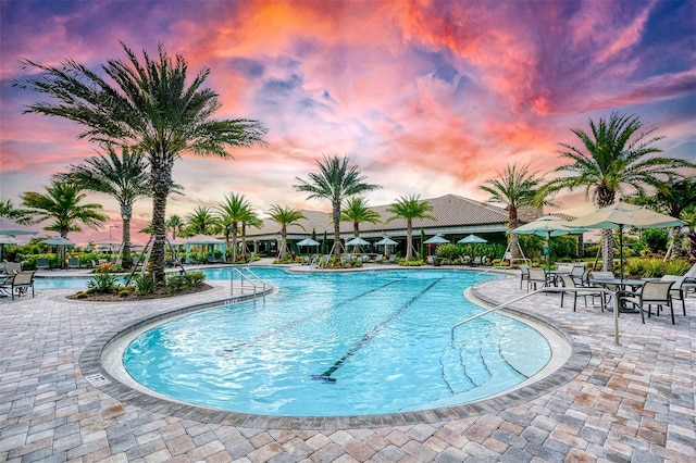 pool at dusk with a patio area