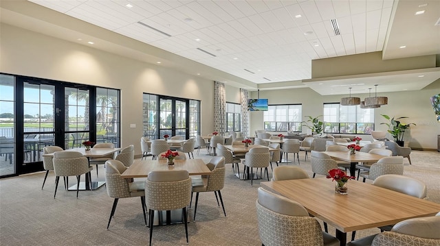 dining space with light carpet, a high ceiling, and french doors