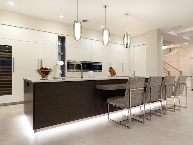 kitchen featuring white cabinets, a large island, pendant lighting, and beverage cooler