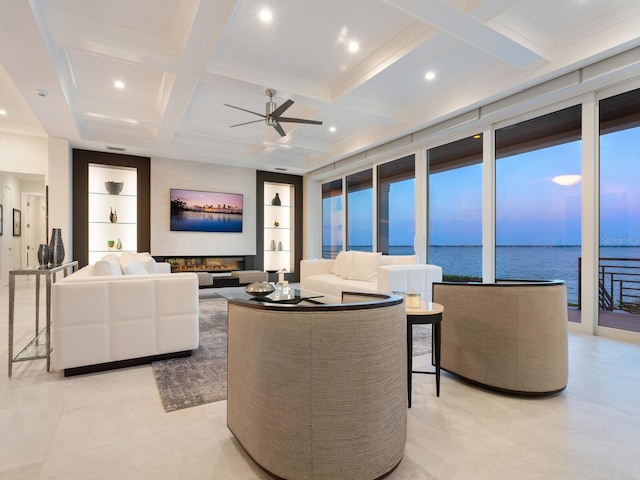 living room featuring coffered ceiling, built in shelves, ceiling fan, a wall of windows, and beamed ceiling